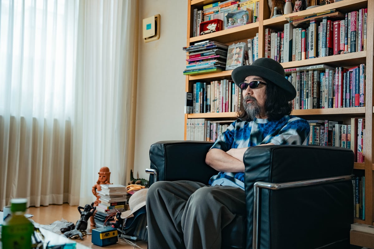 本棚の前に座るみうらじゅんと物たち