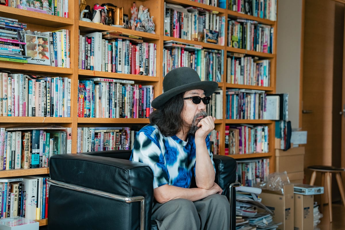 本棚の前に座るみうらじゅん