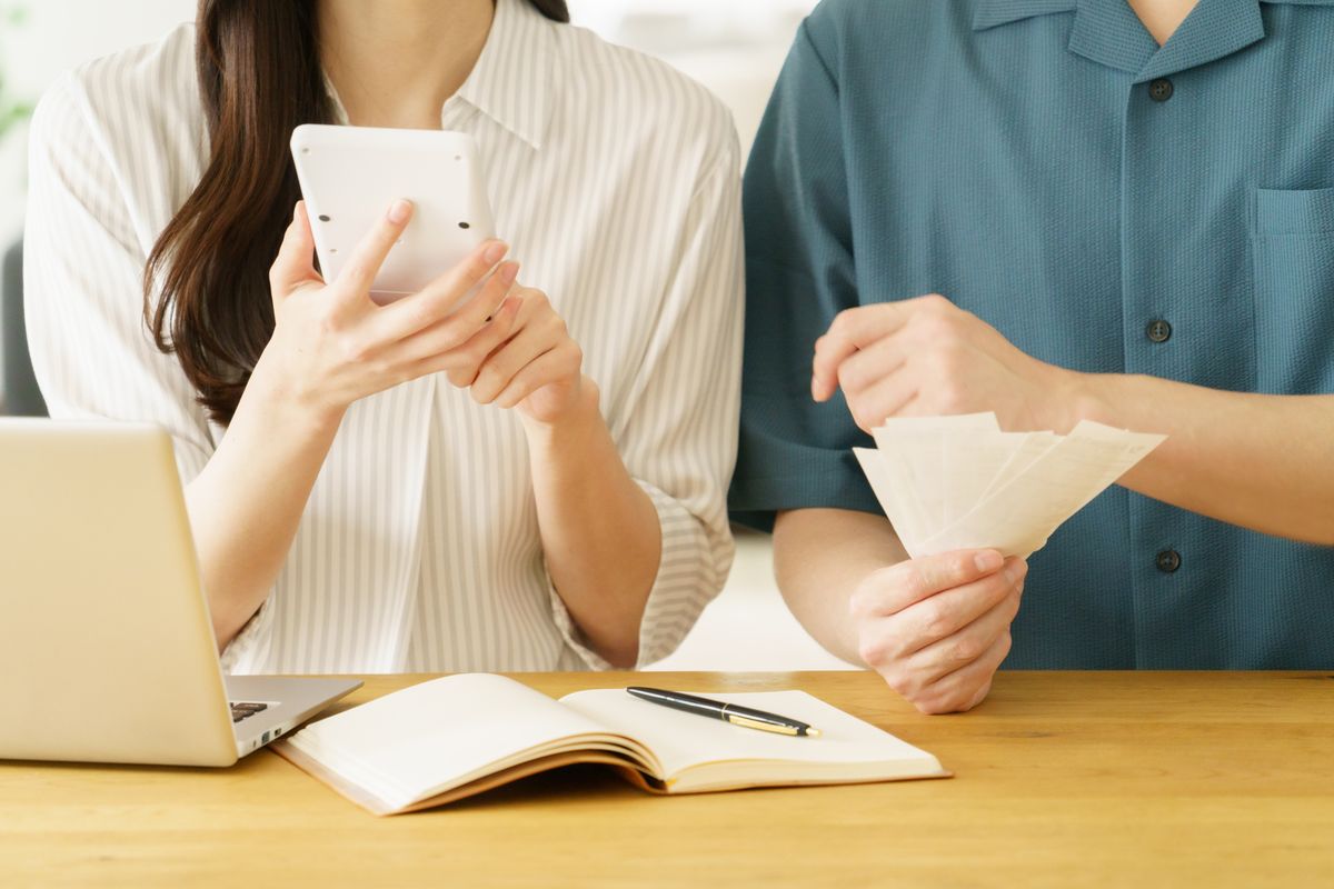 スマートフォンとノートで家計を確認する夫婦