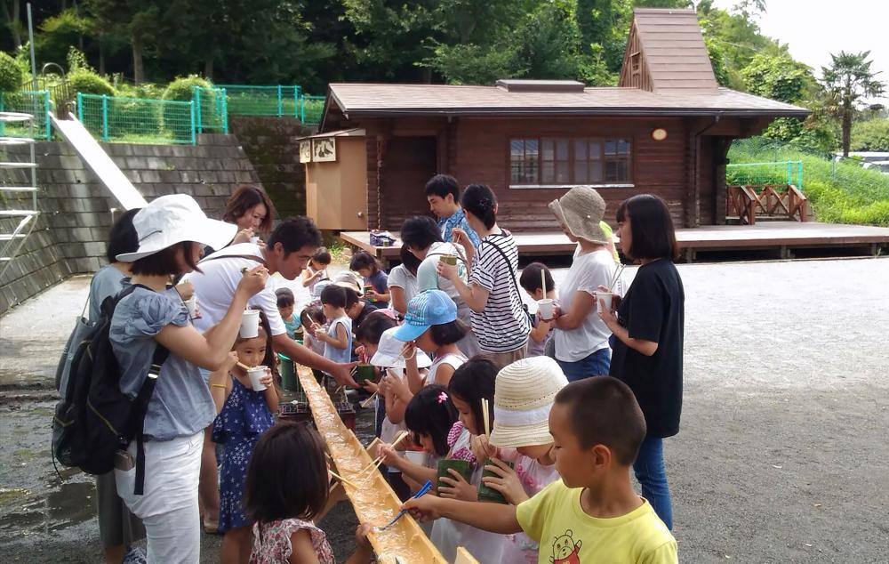集会所の丸太小屋と流しそうめんイベントの様子